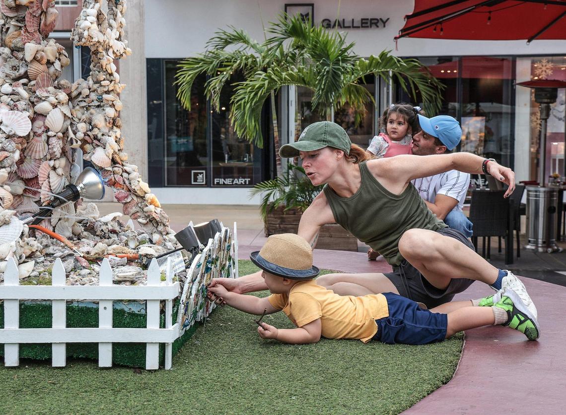 Jillian Taylor holds back her son, Taylor Slato, as he attempts to touch the shells on the menorah. Roger Abramson created a menorah and dreidel out of seashells 20 years ago and it’s still used to celebrate Hanukkah on Lincoln Road. On Nov. 18, Abramson, 87, climbed on a ladder to fix shells that have fallen off.