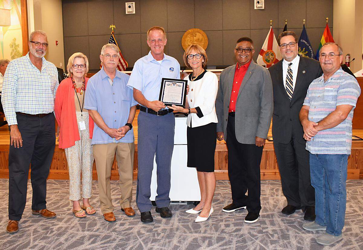 Key West City Commissioners recently honored mail carriers for their annual food drive. Pictured from left to right: Commissioners Gregory Davila, Mary Lou Hoover, Jimmy Weekley, local drive organizer Bob Killen, Mayor Teri Johnston, Commissioners Clayton Lopez, Sam Kaufman and Billy Wardlow.