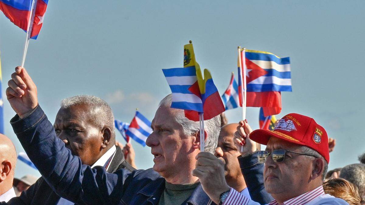 Cuba's President Miguel Diaz-Canel holds Venezuelan and Cuban flags in support of Venezuelan leader Nicolas Maduro in Havana on January 3, 2026, after U.S. forces captured the Venezuelan leader. 