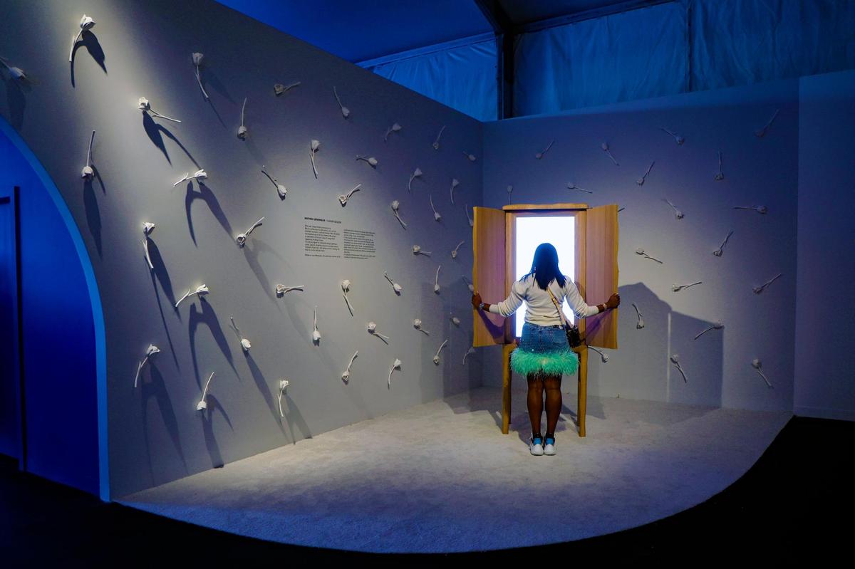 Rhea King views a sky embedded in a carved wooden cabinet with the backdrop of artist Mathieu Lehanneur’s “Flower Season” installation as the fair celebrates its 20th edition with the driving theme of Blue Sky: a celebration of bold leaps in design today at Design Miami on Miami Beach, Florida on Tuesday, December 3, 2024.