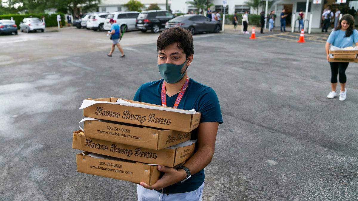 Carlos Echenique, 21, who waited for about 3 hours and 30 minutes, leaves Knaus Berry Farm with freshly baked cinnamon rolls during their opening day in Homestead, Florida on Tuesday, October 26, 2021.