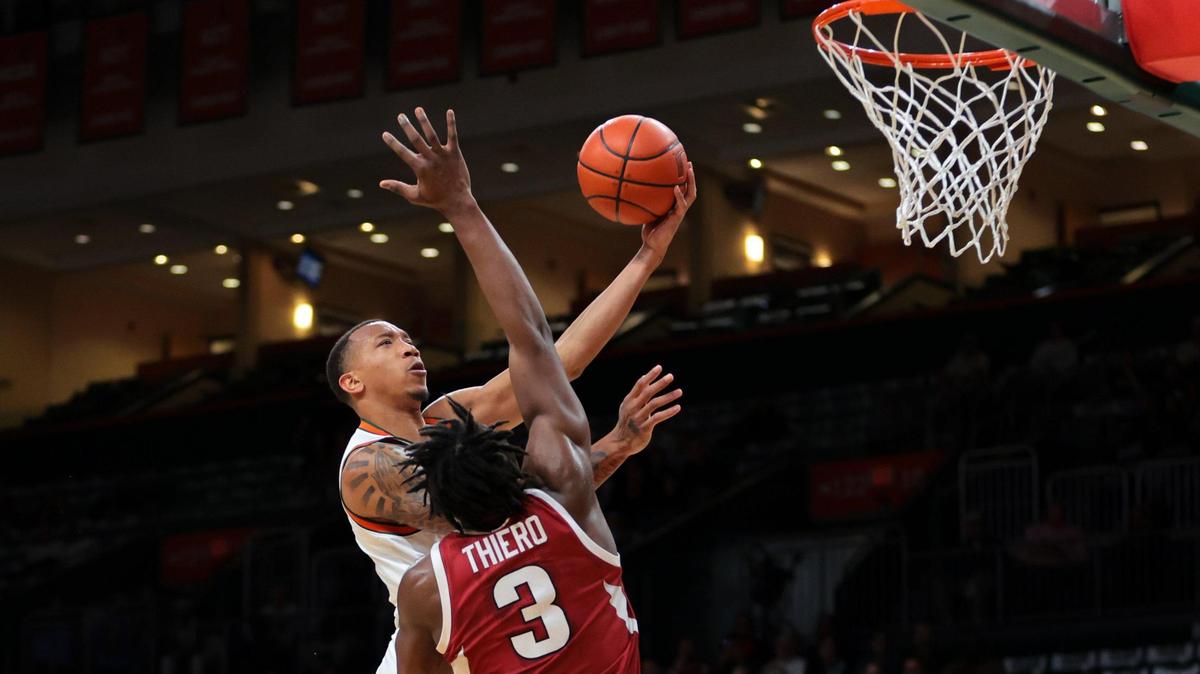 Miami Hurricanes guard Matthew Cleveland (0) scores against Arkansas Razorbacks forward Adou Thiero (3) during the first half at the Watsco Center in Coral Gables, Florida, on Tuesday, December 3, 2024.