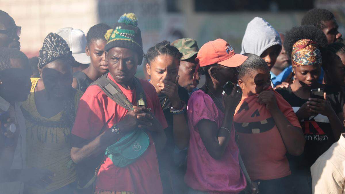 In this file photo, bystanders look at the bodies of alleged gang members that were set on fire by a mob after they were stopped by police while traveling in a vehicle in the Canape Vert area of Port-au-Prince, Haiti, Monday, April 24, 2023.