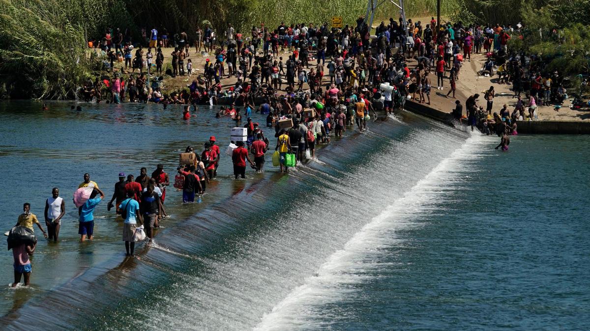 Inmigrantes haitianos usan un dique para cruzar a Estados Unidos desde México, en una imagen del viernes 17 de septiembre de 2021, en Del Río, Texas.