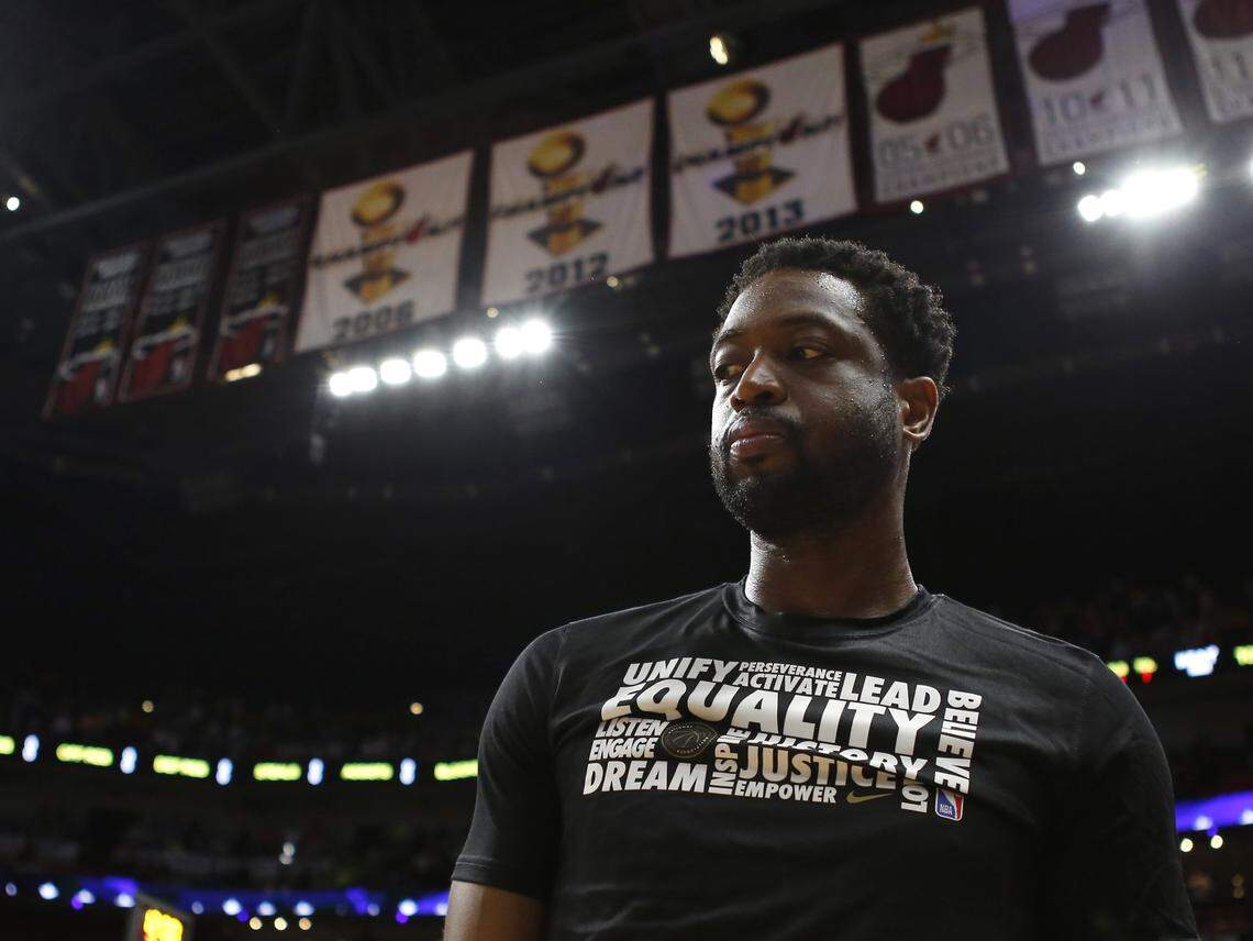With Miami Heat championship banners hanging in the background, Heat guard Dwyane Wade listens to the national anthem before the start of a game against the Oklahoma City Thunder at AmericanAirlines Arena in Miami on Feb. 1, 2019.