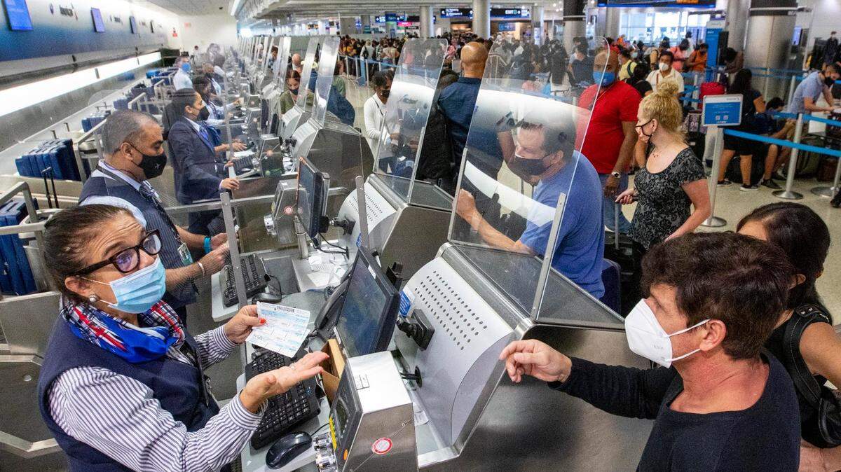 American Airlines employees help travelers check in before their international flight from Miami International Airport in Miami, Florida, on Monday, June 7, 2021.