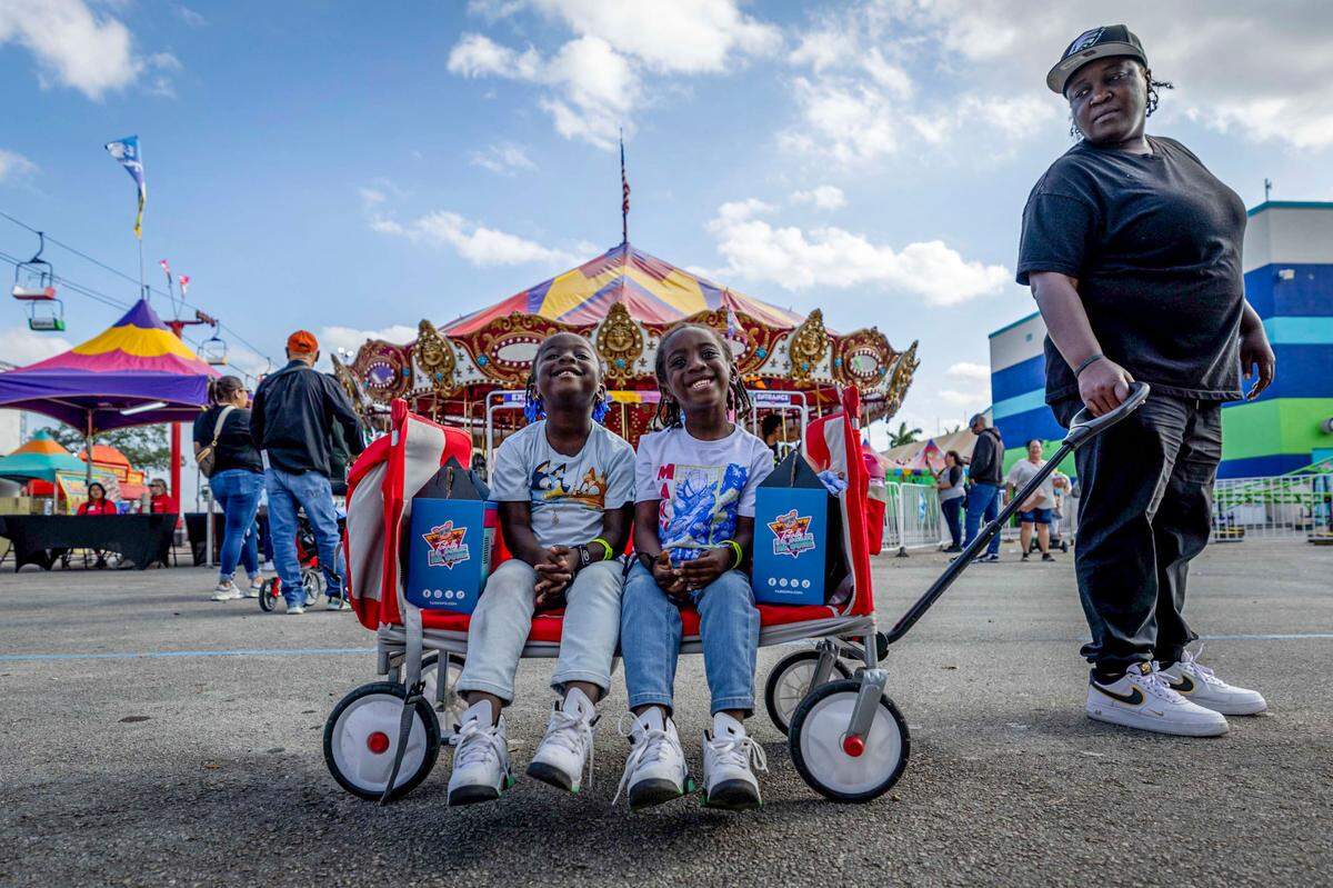 Five year old twins Malaya and Patrick Joseph grin as they are pulled along by mom during the first day of the Miami-Dade County Fair & Exposition