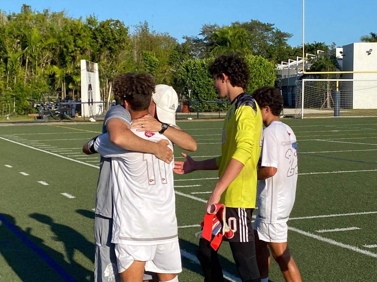Cardinal Gibbons boys soccer coach Rafael Ferreiro hugs midfielder Deni Rivard as the Chiefs celebrate their 1-0 win over Gulliver in the Region 4-4A semifinal on Saturday at Gulliver Prep.