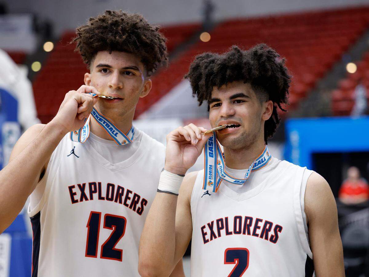 Columbus High School’s Cameron Boozer (12) and brother Cayden Boozer (2) bite their championship medals after defeating Winter Haven during the FHSAA boys basketball Class 7A State Championship at the RP Funding Center in Lakeland, Florida on Saturday, March 4, 2023.