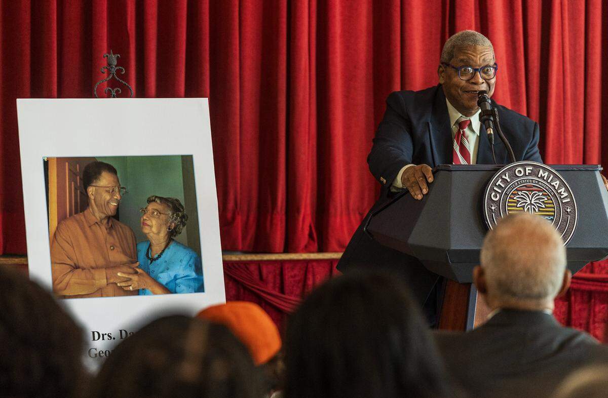 George Simpson Jr. speaks next to a picture of his parents during the street renaming ceremony to honor them, Florida's first board certified Black pediatrician, Dazelle Simpson and her husband the state's first Black surgeon, George Simpson, celebrated at the Christ Episcopal Church, in Coconut Grove, on Friday, January 23, 2026.