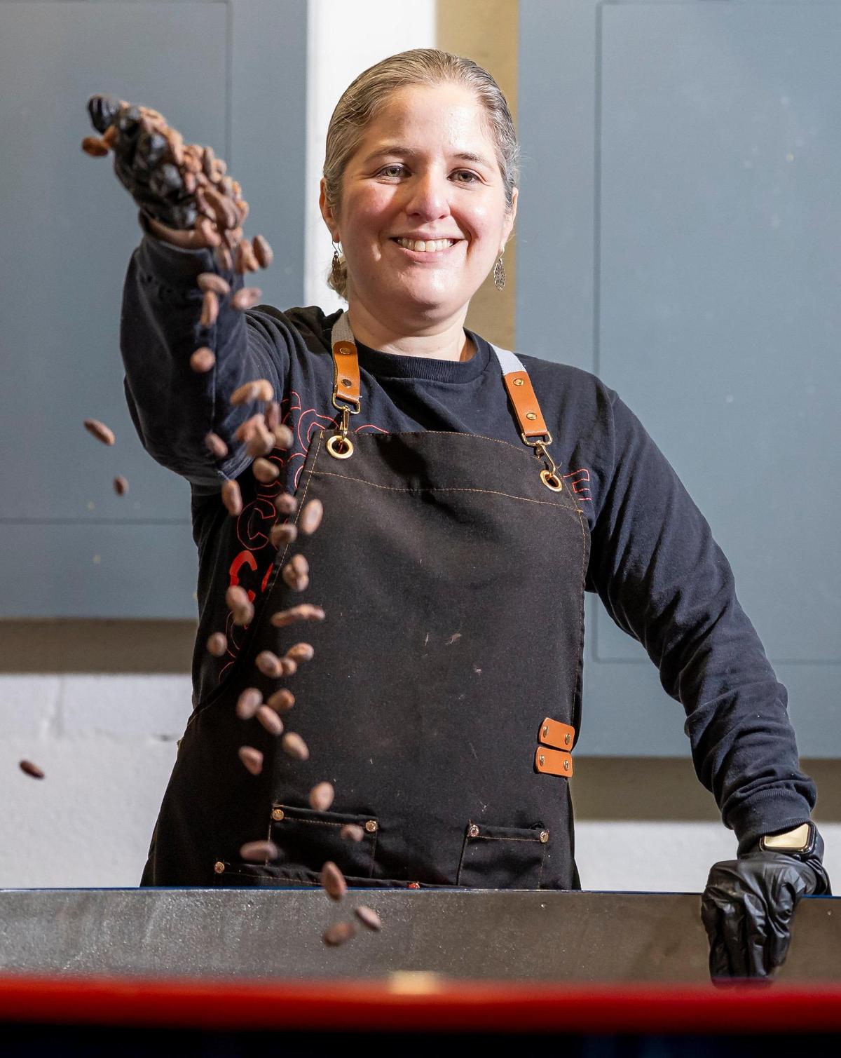 Carolina Quijano grabs cacao beans from her repurposed coffee roaster at the new Exquisito Chocolate factory in Miami.