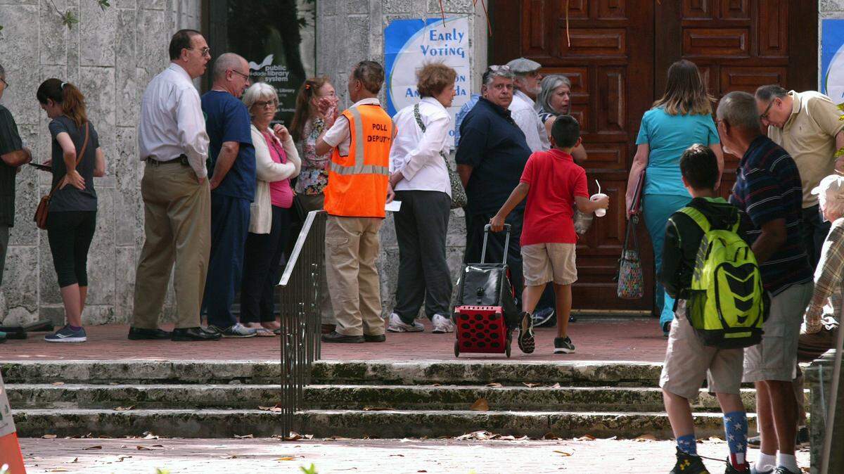 People stand in line for early voting for the 2016 general election at a polling place at the Coral Gables Library.
