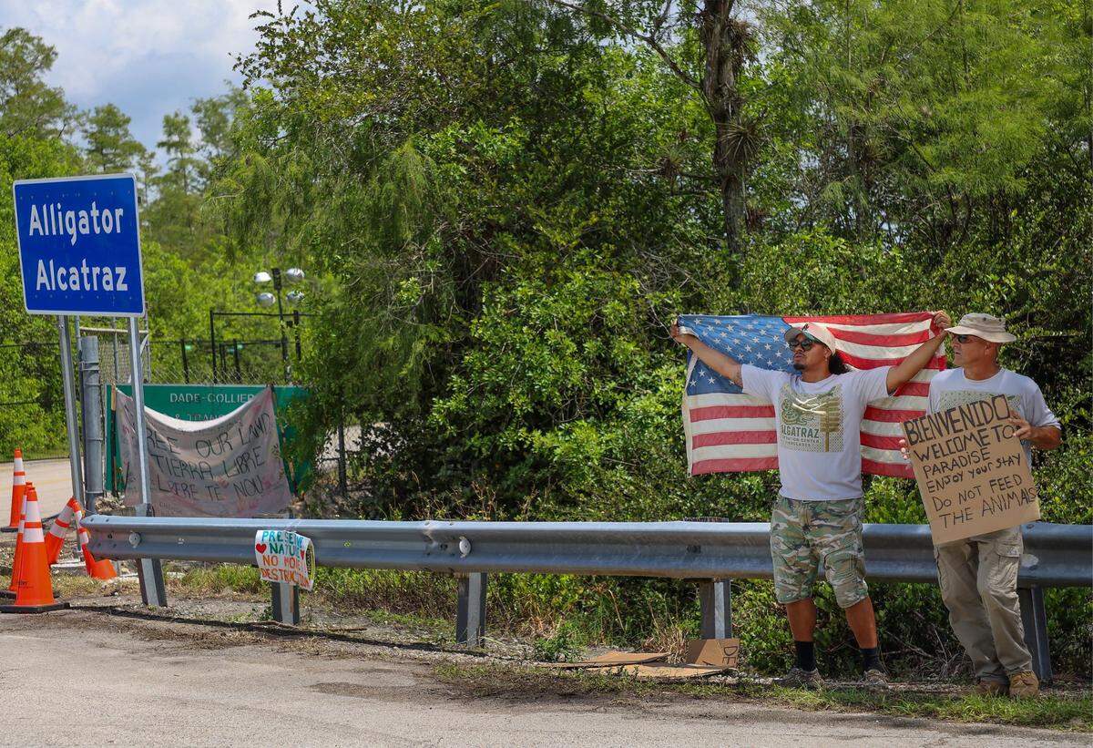 Michigan resident Chris Barrera, Sr., was seen stretching an aged American flag across his back at the entrance of the Dade-Collier Training and Transition Airport, also known as “Alligator Alcatraz.” He stood alongside a friend to show support for the newly constructed detention center located at the Collier and Miami-Dade county line on Sunday, July 6, 2025.