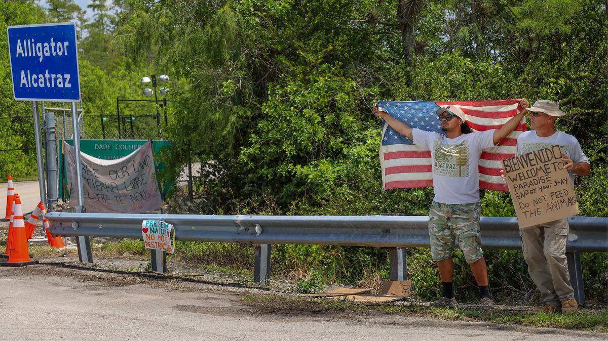 Michigan resident Chris Barrera, Sr., was seen stretching an aged American flag across his back at the entrance of the Dade-Collier Training and Transition Airport, also known as “Alligator Alcatraz.” He stood alongside a friend to show support for the newly constructed detention center located at the Collier and Miami-Dade county line on Sunday, July 6, 2025.