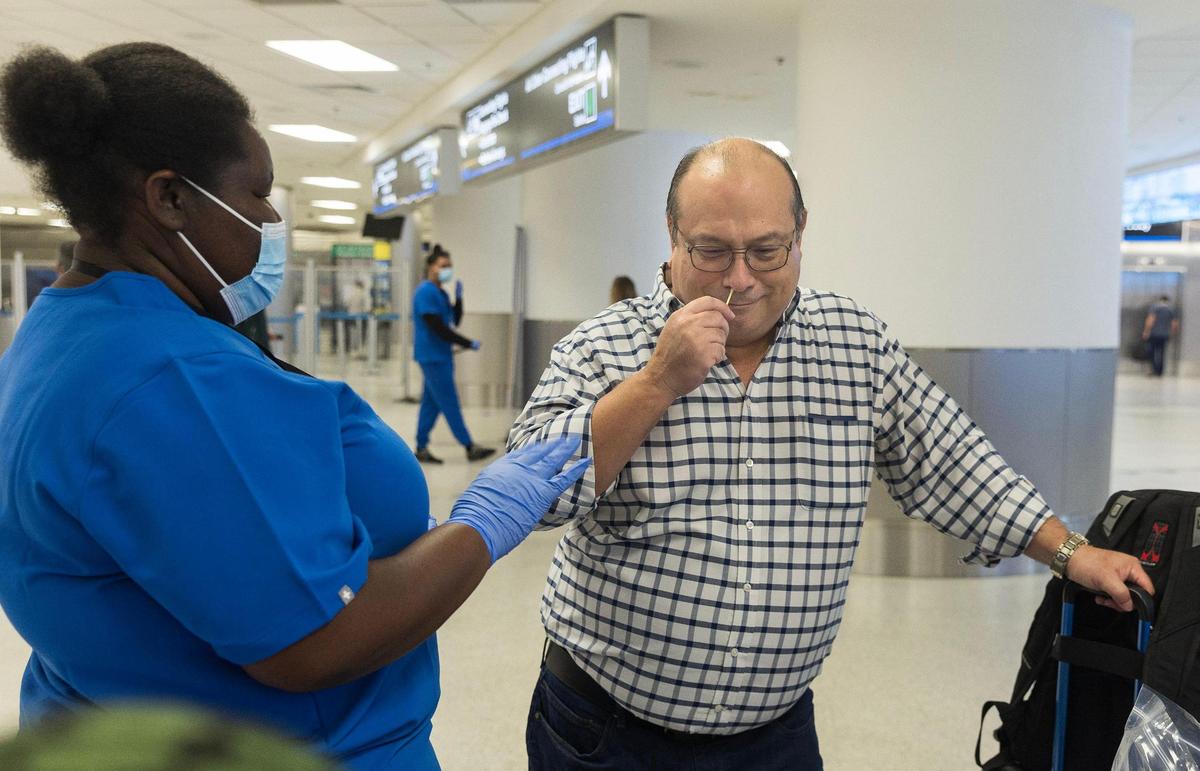 Bio surveillance specialist Jaymersha Wright assists traveler Carlos Avila arriving from Barbados as he swabs his nose for a voluntary test as some travelers flying into Miami from other countries are being asked to do a nose swab to test for COVID variants and other contagious viruses as part of a nationwide effort to track new and emerging infectious diseases, on Thursday, March 14, 2024.