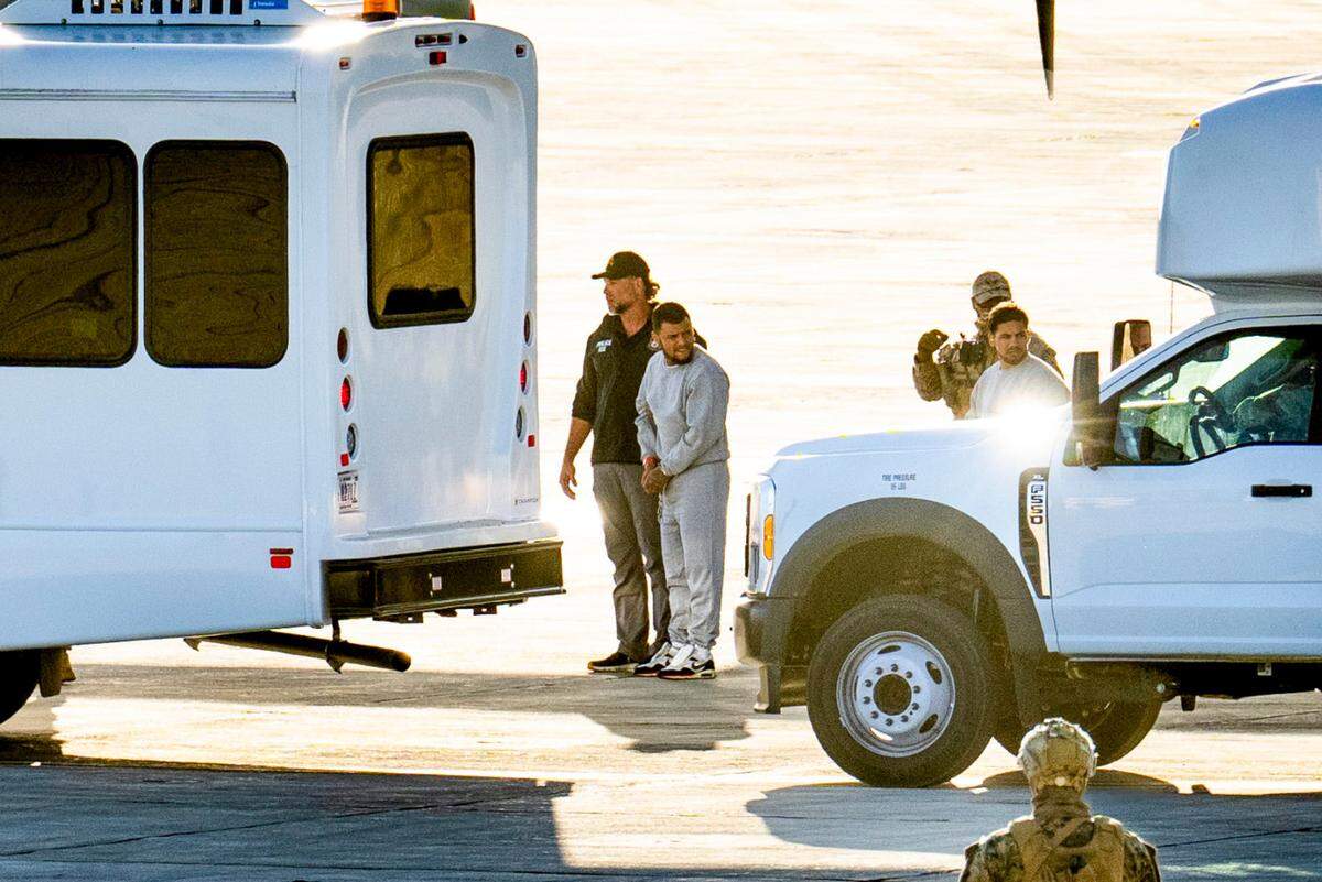 Security forces escort Yoiner Jose Purroy Roldan off a C-130 military plane at the U.S. naval base at Guantanamo Bay, Cuba, Feb. 7, 2025. His mother said she recognized him in this photo. (Doug Mills/The New York Times)