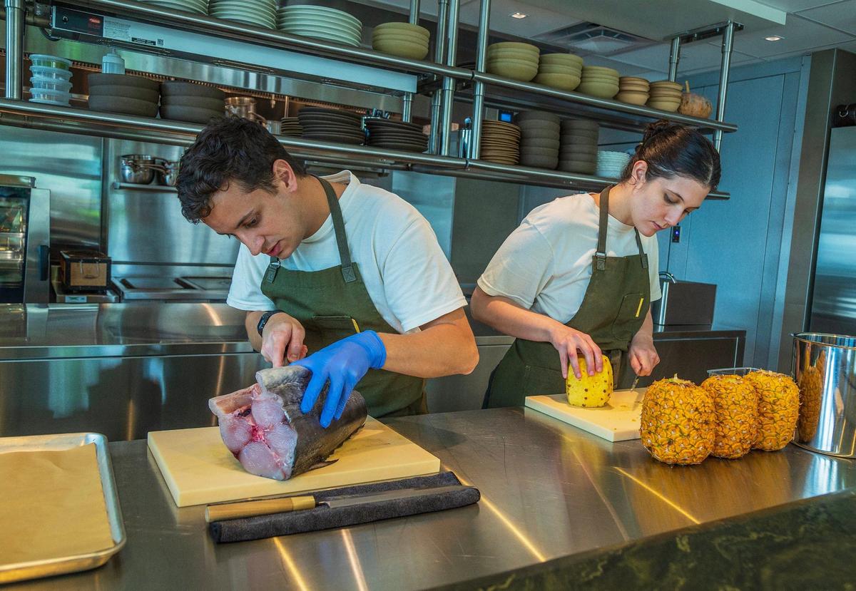 Nico Martínez prepares wahoo while Maria Teresa Gallina slices a pineapple in the kitchen of their recently opened restaurant Recoveco.