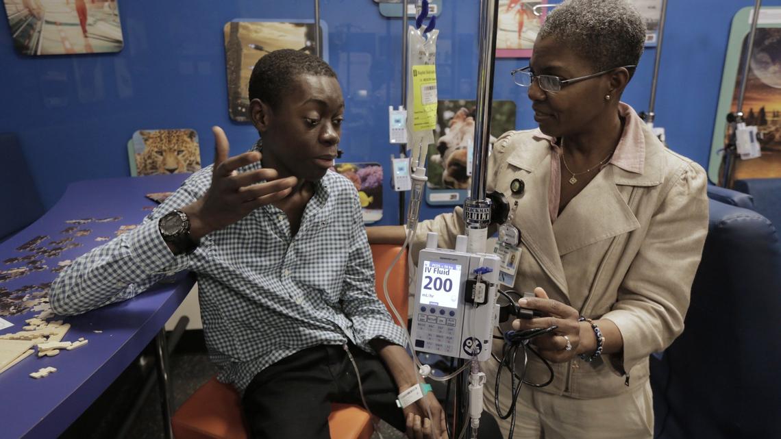 Djonsly Alcin, 14, talks to Baptist Health nurse Martha Pearson during chemotherapy. Djonsly, who is from Haiti, suffers from optic pathway glioma, a slow-growing brain tumor. His advanced cancer has also spread down his spine.