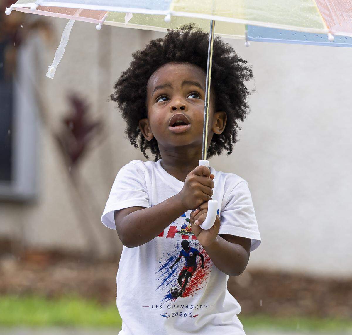 Saba Dumornay, 2, uses an umbrella to stay dry while waiting for a meet-and-greet with the Haiti national soccer team at the Museum of Contemporary Art on Saturday, May 30, 2026, in North Miami, Fla.