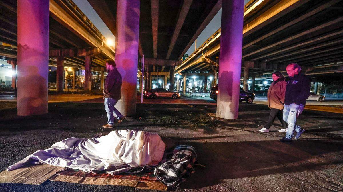 Homeless people sleep under an Interstate 95 overpass as Ron Book, chair of the Miami-Dade Homeless Trust (right), joins others during the Trust’s biannual census count in Miami in January.