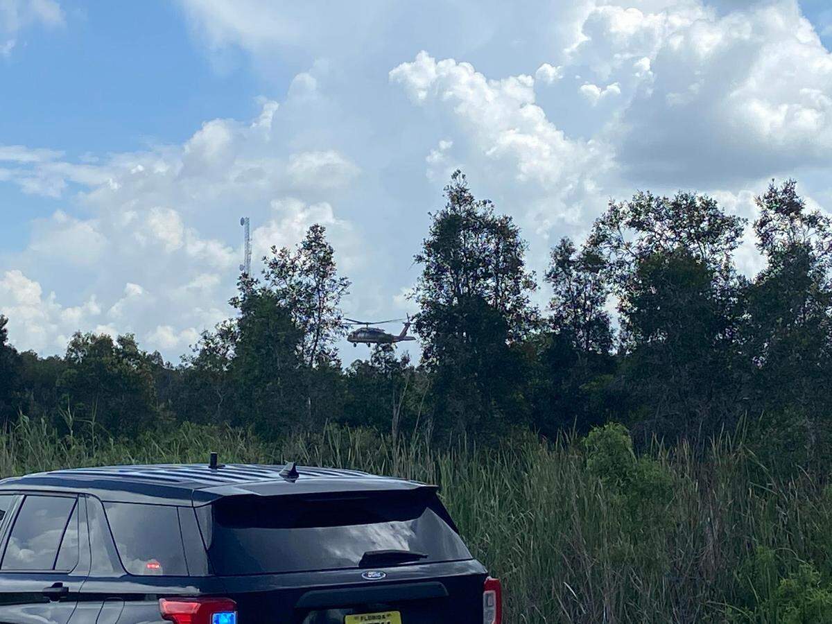 A U.S. Customs and Border Protection Black Hawk helicopter hovers over the trees along Krome Avenue and Southwest Eighth Street Thursday, Aug. 22, 2024, as part of a large search for a man who escaped Krome Detention Center on Wednesday.