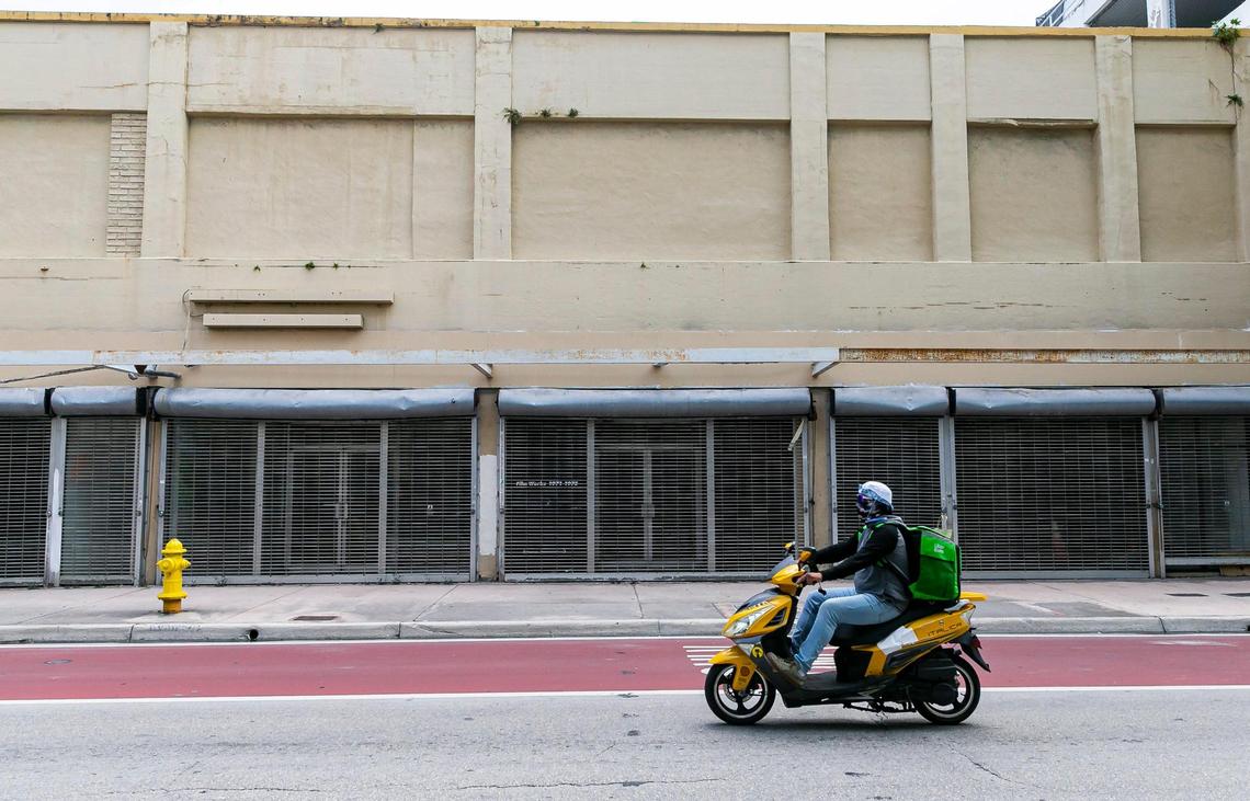 A motorist makes his way past shuttered storefronts belonging to billionaire entrepreneur Moishe Mana on Southeast First Street in downtown Miami.