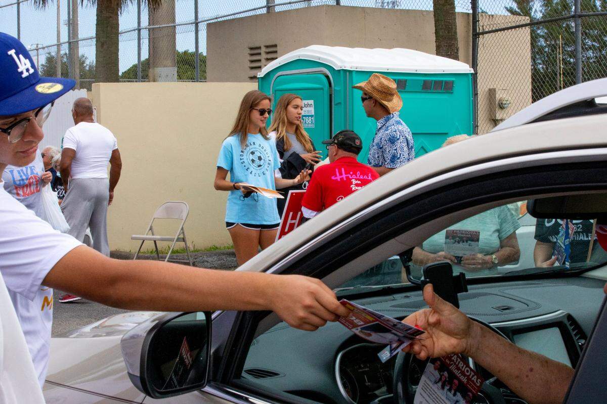 Student volunteers with My Vote Project pass out information to voters outside the JFK Library in Hialeah on Saturday, a polling place conducting early voting before Tuesday’s Hialeah mayoral and city council election.