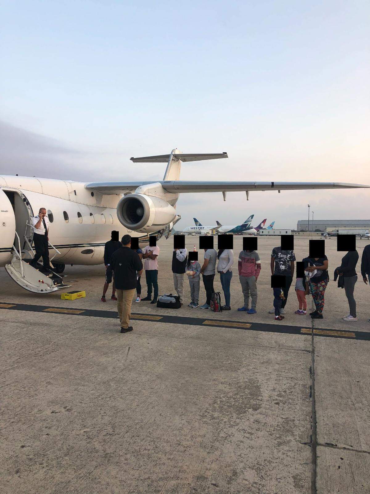 Migrants, their faces obscured, outside the plane that ferried them from Texas to Martha's Vineyard, Massachusetts. When the DeSantis administration looked to book more flights, it turned to ARS and GardaWorld.
