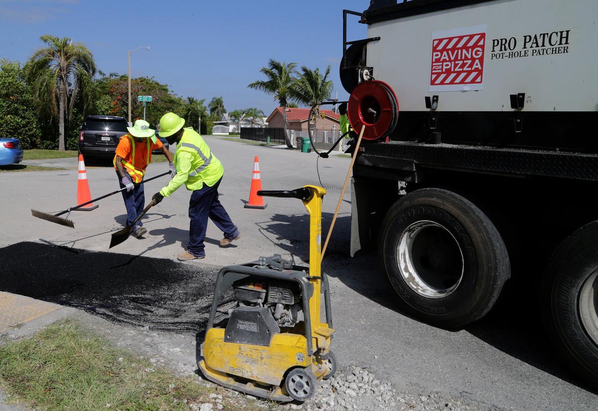 Miami-Dade County public works department employees work on a street pothole off of Southwest  137th Avenue, as  dozens of potholes are been fixed thanks to a $5,000 grant by Domino’s Paving for Pizza program in the Kendall area.