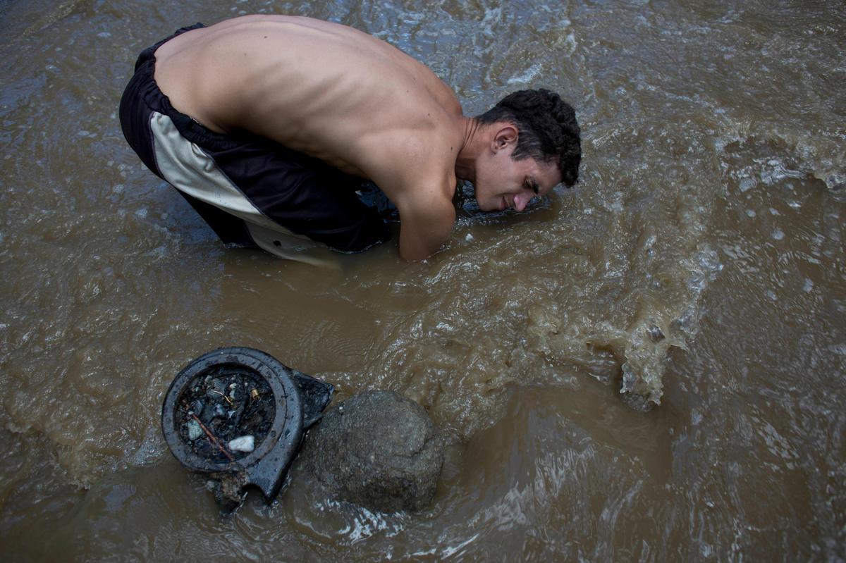 David Garcia, de 19 años y padre de un bebé de 4 meses, busca cualquier cosa de valor en el fondo del río Guaire, en Caracas, Venezuela.