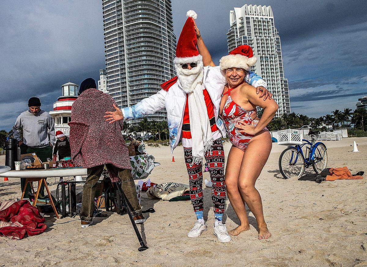 In this file photo from Dec. 24, 2022, as Miami hit a low of 48, Marina Mak, of South Beach, posed with her friend Mario Fauret after taking a swim as she joined a group of friends and swimmers that celebrated Christmas in South Pointe, Miami Beach, despite the cold temperatures. The Dec. 24-25, 2024, Christmas-Hanukkah holiday promises to be considerably warmer, around 80, with just a small chance of rain.