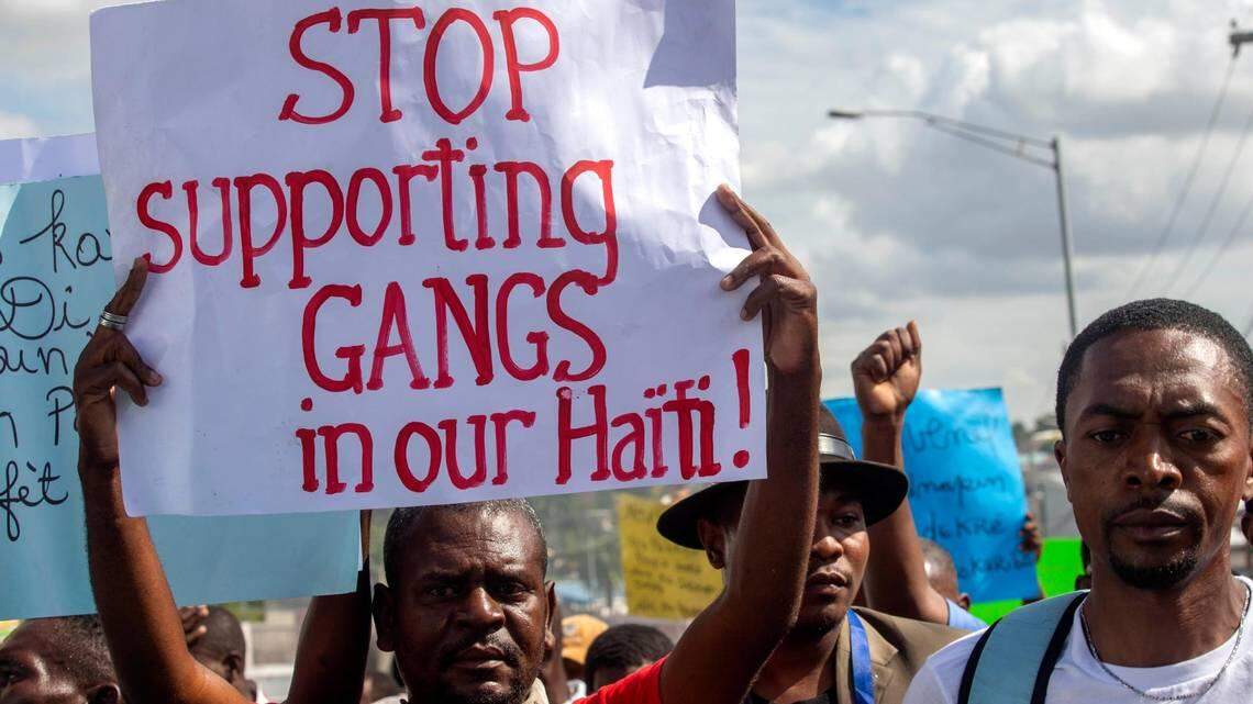 A protester in Port-au-Prince, Haiti, holds up a sign in 2020 demanding that support of violent gangs in Haiti end.