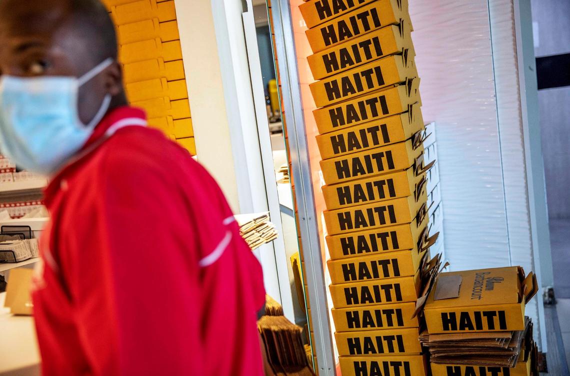 Boxes of rum are stacked against a wall as a duty-free employee wearing a mask works at Toussaint Louverture International Airport, in Port-au-Prince, Haiti, March 14, 2020.