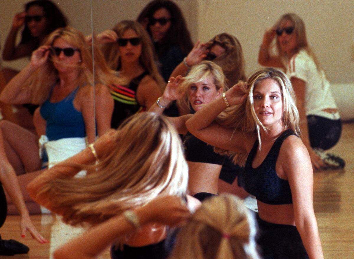 Dorie Braddy, the Dolphins' director of cheerleaders, shows the other cheerleaders how to make a certain hair move.