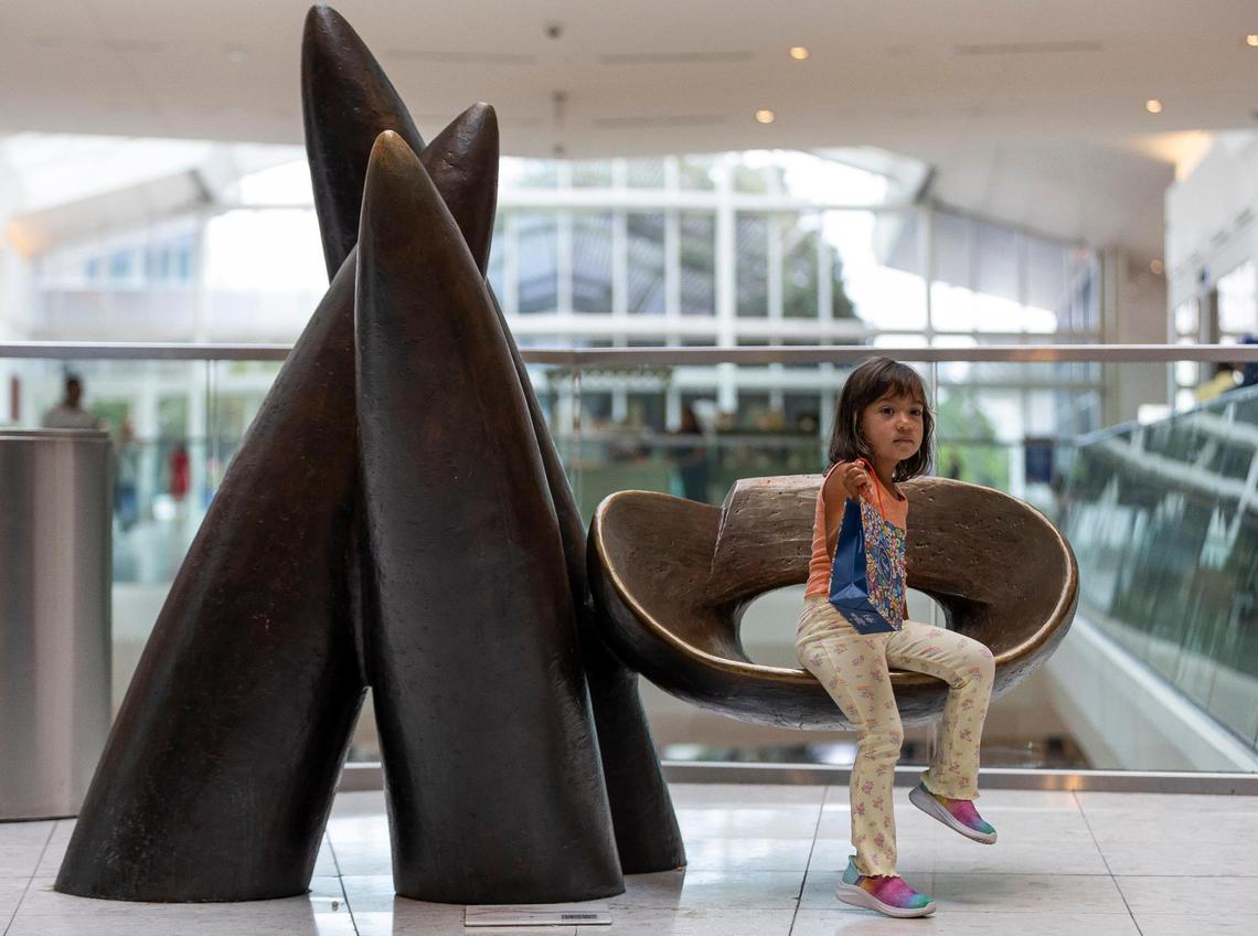 Alma Outy, 3, sits on ‘Veiled in a Dream,’ a bronze sculpture by Wendell Castle, one of the many art installations available for visitors to see at Aventura Mall on Wednesday, Sept. 25, 2024, in Aventura, Fla.