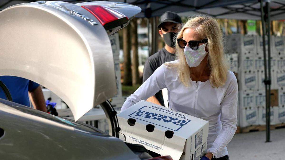 In December, Georgi Miller loads a box of fresh vegetables into a vehicle at a food distribution event in Miami Beach.
