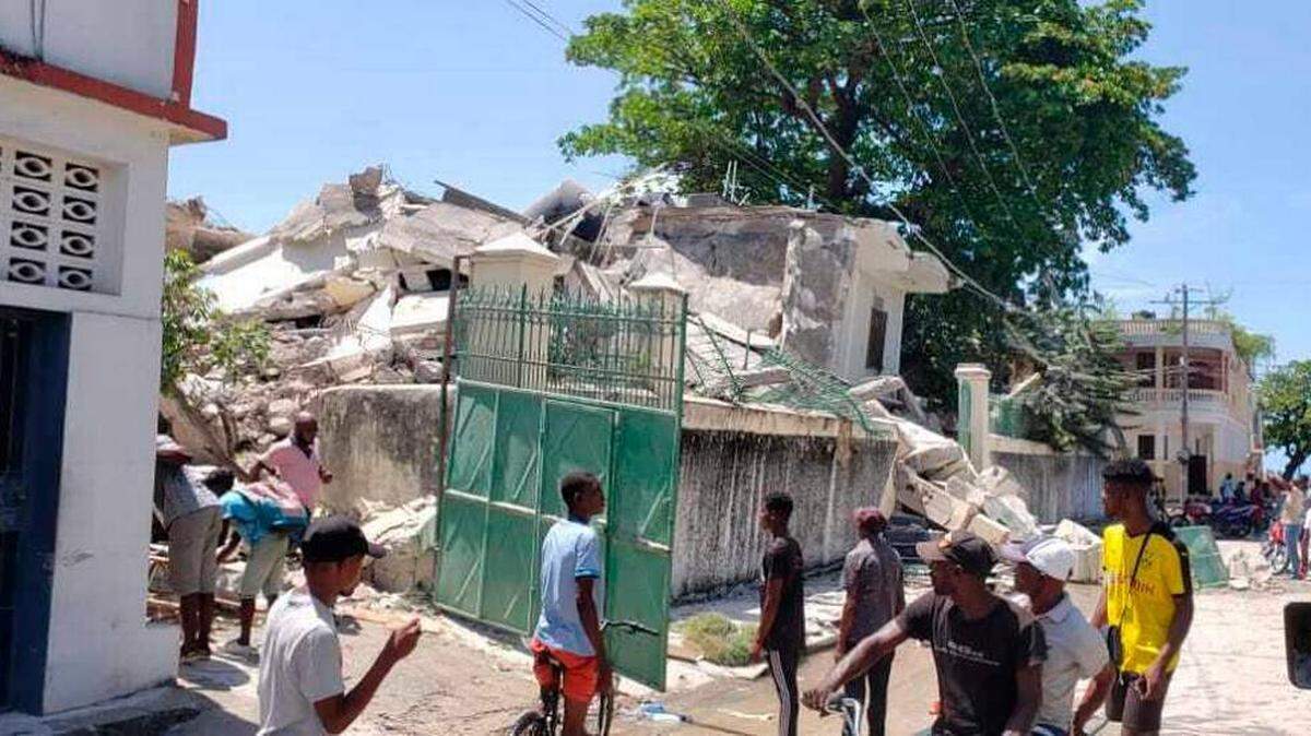 People in Les Cayes, Haiti, stand outside the residence of the Catholic bishop after it was damaged by an earthquake in August 2021.
