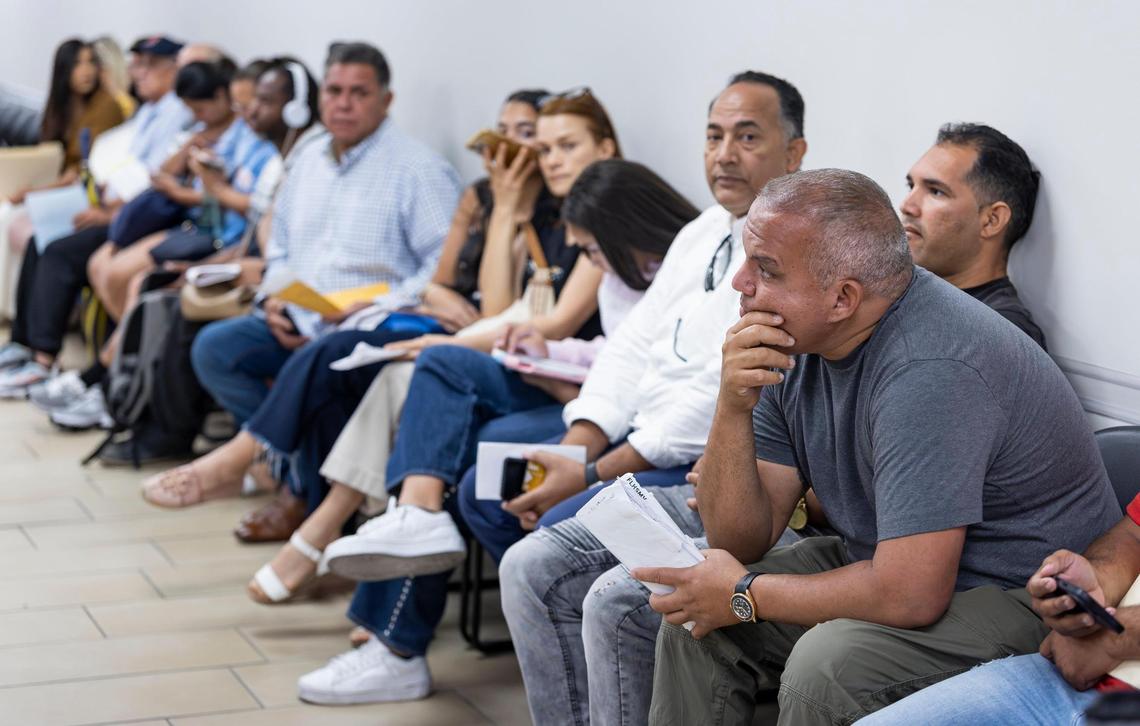 Mariano Macias, de 43 años, extrema derecha, espera su turno junto a otros de un Centro de Servicio de Licencias de Conducir y Vehículos Motorizados de Seguridad en las Carreteras y Vehículos Motorizados de Florida el miércoles 16 de abril de 2025, en Miami, Florida.