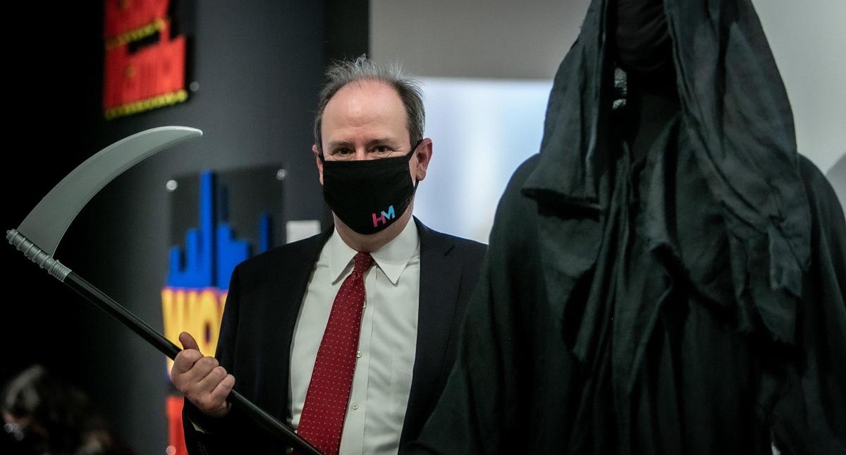 Daniel Uhlfelder, who walked around the beach dressed as the Grim Reaper, poses next to the costume he wore to warn beachgoers of the dangers of COVID-19.