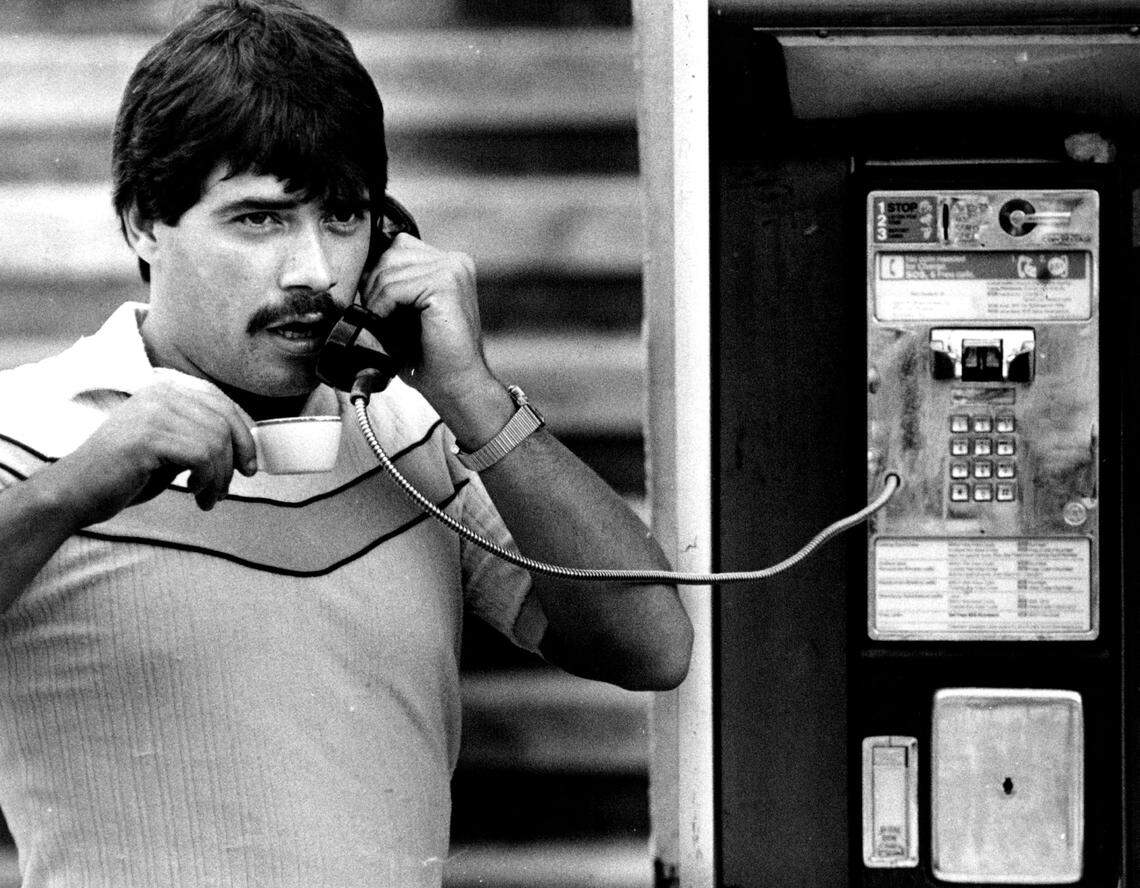 Nicholas Gonzalez talks to a friend on a payphone, with a cup of Cuban coffee in hand on Okeechobee Road in Miami-Dade.