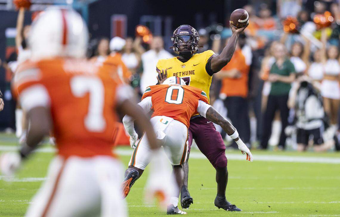 Bethune-Cookman Wildcats quarterback Timmy McClain (7) throws the ball as Miami Hurricanes defensive back Keionte Scott (0) tries to tackle him in the first half of their NCAA football game at Hard Rock Stadium on Saturday, Sept. 6, 2025, in Miami Gardens, Fla.