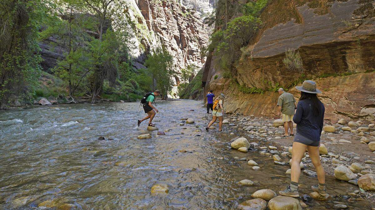 Hikers take pictures at the entrance of the famous Narrows hike, currently closed, along the North Fork of the Virgin River in Zion National Park on May 15, 2020 in Springdale, Utah.