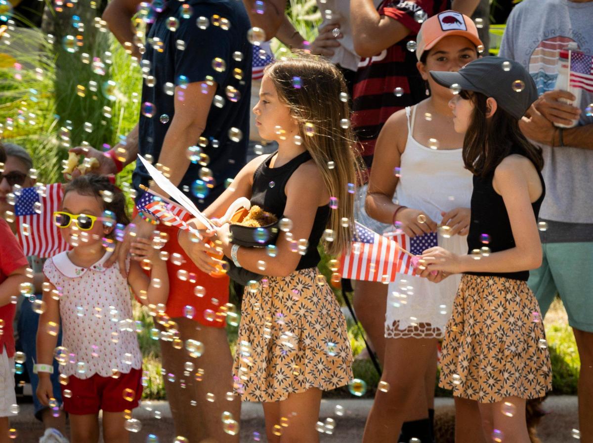 At a parade on Key Biscayne, Josefa Munoz, center with no hat, and Filipa Iraguen, right, watch the Fourth of July marchers along Crandon Boulevard.