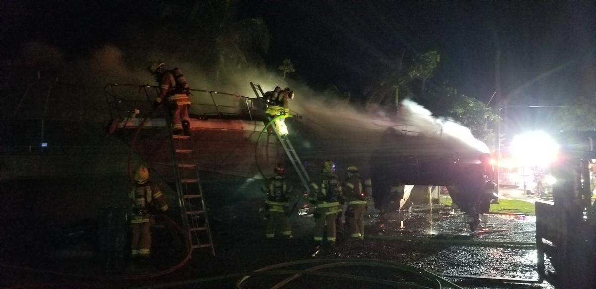 Islamorada Fire Rescue firefighters climb onto a smoldering boat at the Coral Bay Marina in Upper Matecumbe Key Monday morning, Feb. 11, 2019.
