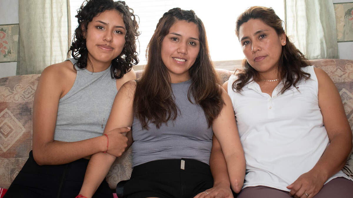 Brigite Valverde, en el centro, con su hermana Wara (izquierda), y su madre, Brenda, se trasladaron de Bolivia a Opa-locka, en Miami, con la esperanza de que Brigite pueda conseguir una prótesis de brazo funcional.