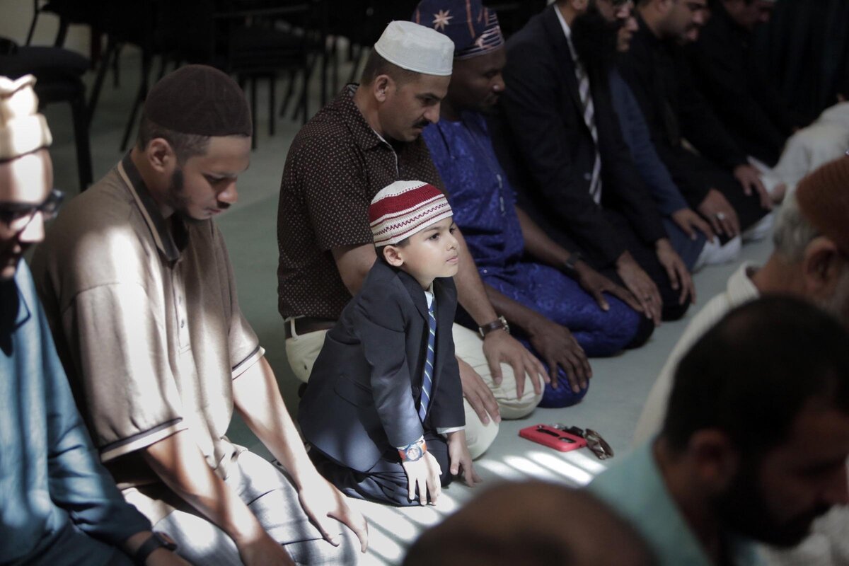 Five year old Asmir Butt joins his father Tahir Ahmad (on the right of the boy, wearing white cap) and other members of the  Baitul Naseer Mosque, 208 NW Seventh Ct., Hallandale Beach for a prayer service.