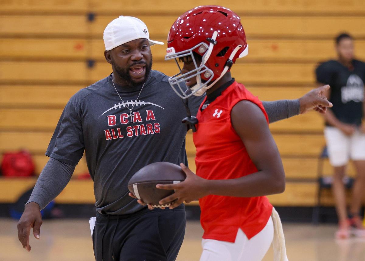 Monarch High football head coach Calvin Davis, left, instructs a player during practice as the team held their practice inside the school’s gym due to bad weather and lightning on Monday, July 31, 2023 in Coconut Creek, Florida.