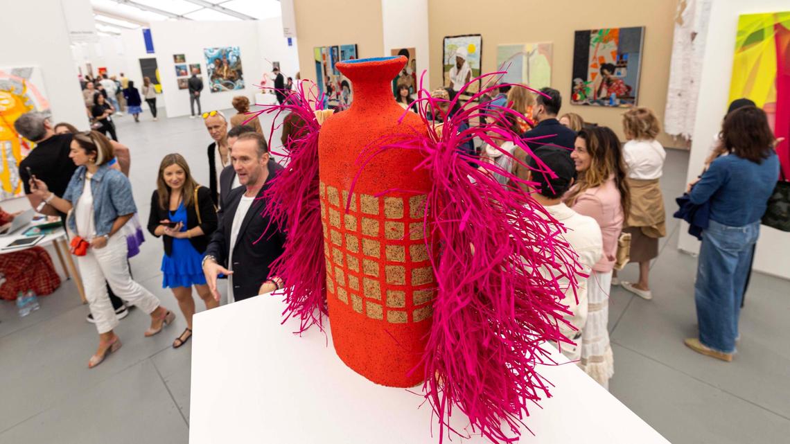Guests walk past Alfred Lowe’s ceramic pieces at UNTITLED on Tuesday in Miami Beach.