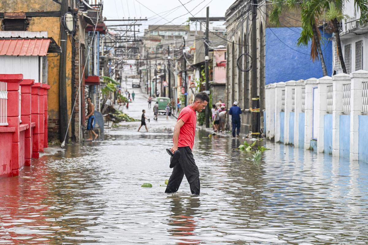 A man walks through a flooded street in a neighborhood affected by Hurricane Melissa in Santiago de Cuba on October 29, 2025. A powerful Hurricane Melissa made landfall in eastern Cuba on Wednesday, causing damage and flooding to homes and streets in Santiago de Cuba province, an AFP team on the ground reported. 