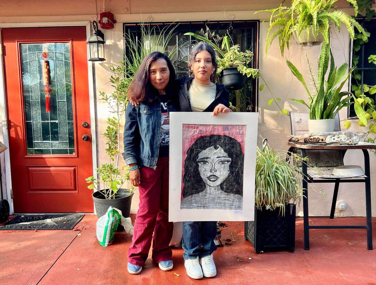 Rosa Castellanos, left, and her daughter hold a portrait Emily painted in a class.